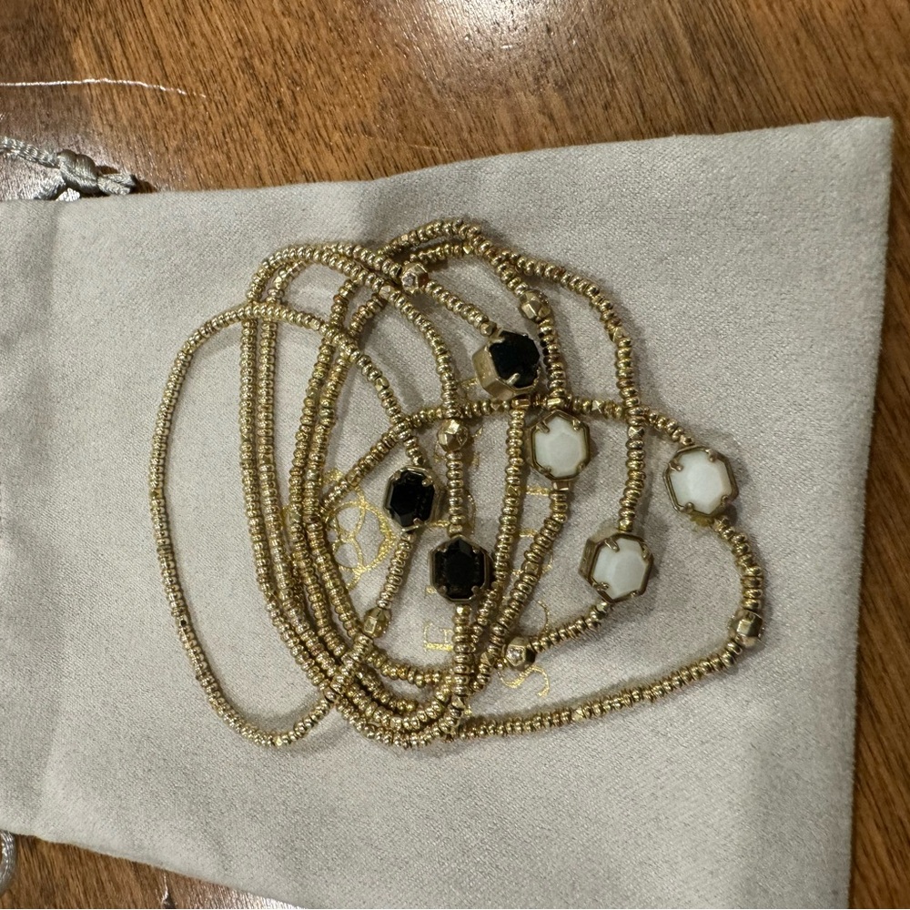 Set of 6 gold stretch bracelets with white and black stones.